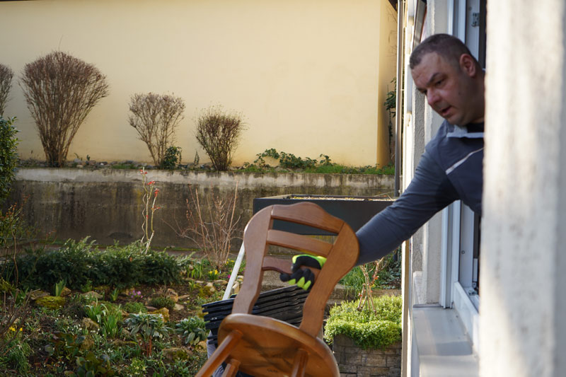 Tontshew Mitarbeiter reicht Stuhl durch Fenster während Entrümpelung Jettingen