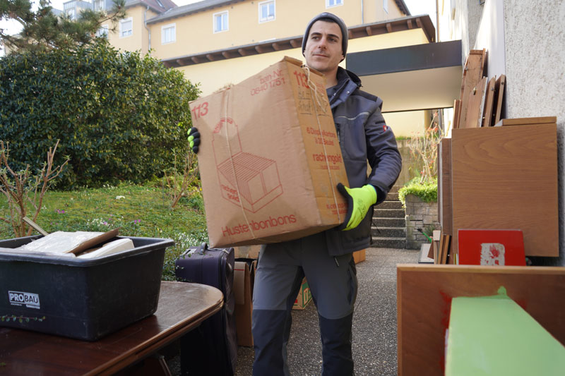 Tontshew Mitarbeiter trägt eine Kiste aus der Wohnung während Entrümpelung Waiblingen