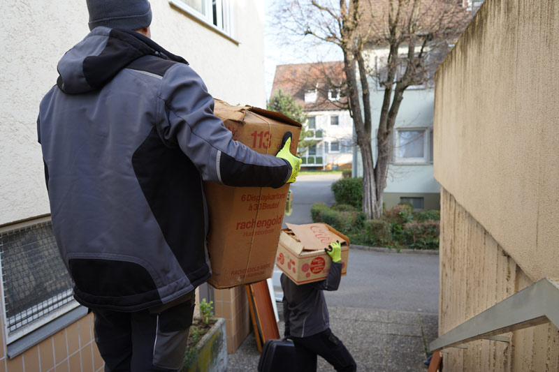 Tontshew Mitarbeiter tragen Kisten aus der Wohnung während Entrümpelung Weil der Stadt