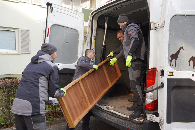Tontshew Mitarbeiter tragen schwere und lange Holzplatte in Sprinter während Entrümpelung Wendlingen